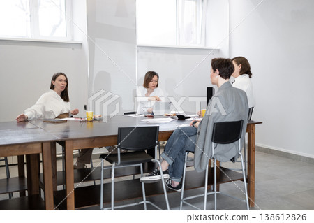 Women chatting and finishing up business meeting with notepads and cups on table in office. Chatting, notepads, meeting, office, business, women. 138612826