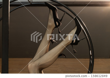 Woman legs fishnet stockings and high heels on a black metal structure fashion beauty industry 138612849