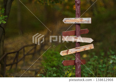 A rustic wooden signpost with multiple directional arrows in a forest setting with a blurred background A rustic wooden signpost with multiple directional arrows in a forest setting with a blurred background 138612908