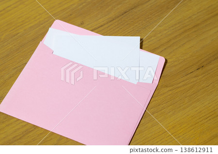 Pink envelope with white cards on a wooden table surface message text pattern copy space background 138612911