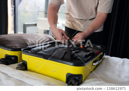 Young man packing suitcase on bed at home before travel Young man packing suitcase on bed at home before travel 138612971