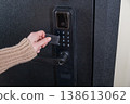 A woman opens a modern smart door lock using a contactless key. 138613062