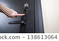 A woman opens a modern smart door lock with a digital keypad using a code. 138613064