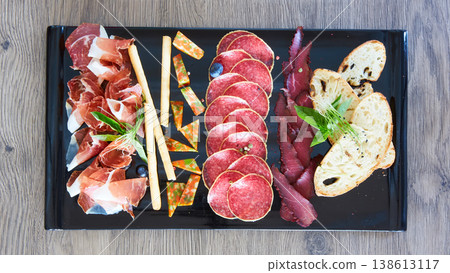 A multi-sensory charcuterie board featuring premium sliced salami, prosciutto 138613117