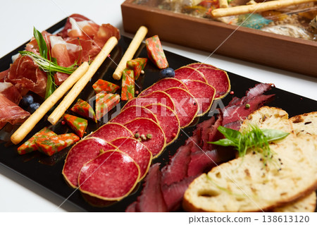 A multi-sensory charcuterie board featuring premium sliced salami, prosciutto 138613120