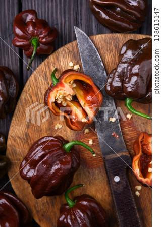 Chocolate habanero peppers with knife and cut halves on wooden board Chocolate habanero peppers with knife and cut halves on wooden board 138613147