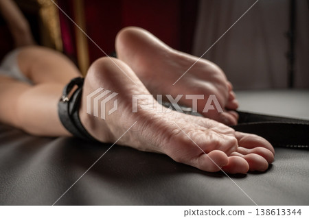 Women's legs in leather shackles. BDSM fetish. Women's legs in leather shackles. BDSM fetish. 138613344