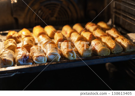 Homemade Crepe Rolls Baking on a Tray Inside a Modern Oven 138613405