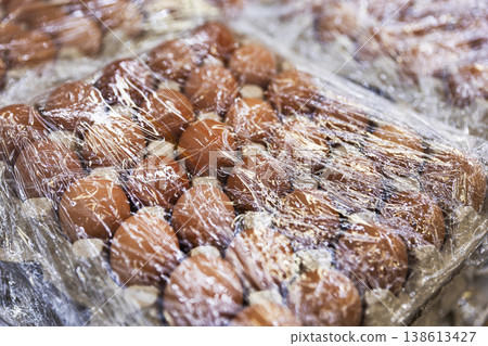 Close-up of Brown Chicken Eggs in Cardboard Tray Wrapped in Plastic Film 138613427