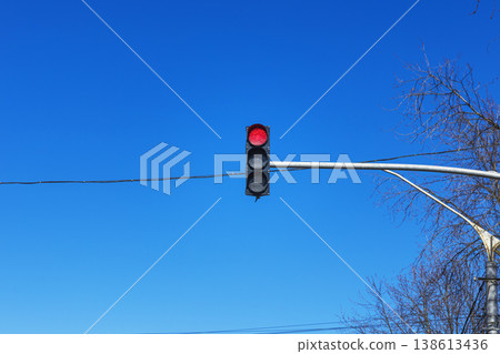 Red Traffic Light Hanging on a Pole against a Clear Bright Blue Sky 138613436