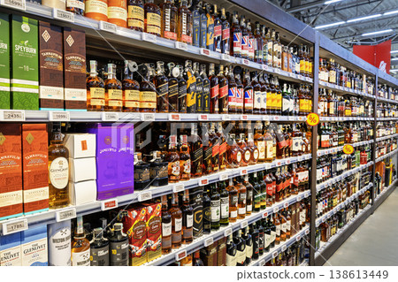 Large selection of whiskey and scotch bottles on shelves in Auchan hypermarket 138613449