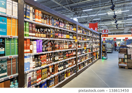 Wide selection of whiskey and scotch bottles on shelves in Auchan hypermarket 138613450