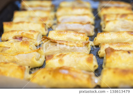 Rows of Golden Meat Crepe Rolls on a Baking Tray in the Kitchen Rows of Golden Meat Crepe Rolls on a Baking Tray in the Kitchen 138613479