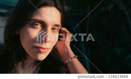 Young woman close portrait with soft gaze in golden sunlight Young woman close portrait with soft gaze in golden sunlight 138613669