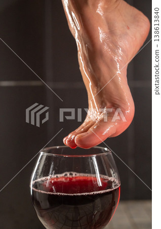 Foot fetish. A woman dips her toes in a glass of red wine. Foot fetish. A woman dips her toes in a glass of red wine. 138613840