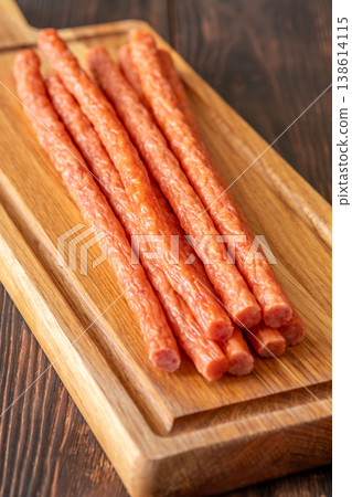 Smoked kabanos sausages arranged on rustic wooden board showcasing traditional savory meat snack texture Smoked kabanos sausages arranged on rustic wooden board showcasing traditional savory meat snack texture 138614115