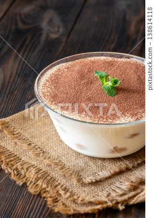 Classic Italian tiramisu dessert in glass bowl with cocoa powder and fresh mint 138614118