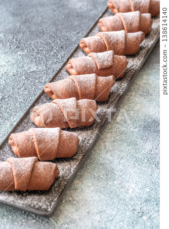 Chocolate croissants dusted with sugar on slate platter bakery top view composition Chocolate croissants dusted with sugar on slate platter bakery top view composition 138614140