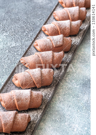 Chocolate croissants dusted with sugar on slate platter bakery top view composition 138614141
