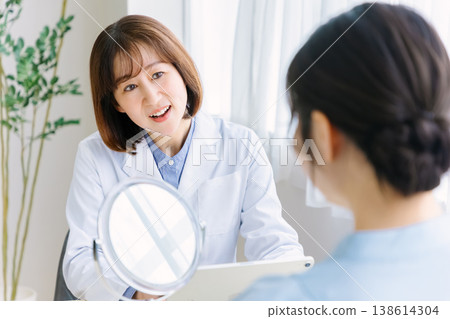 A woman receiving a consultation and examination from a doctor at a cosmetic surgery clinic. 138614304