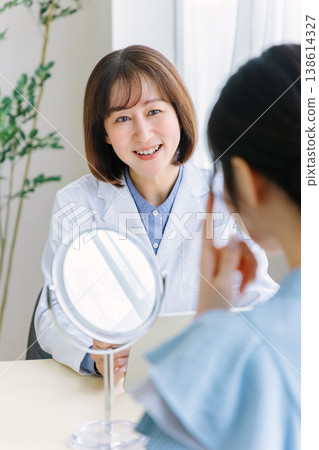 A woman receiving a consultation and examination from a doctor at a cosmetic surgery clinic. 138614327