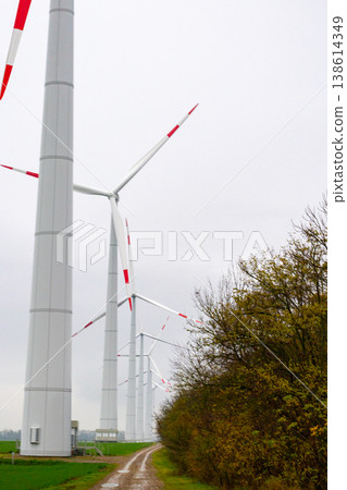 wind turbines in field rotate their blades to generate energy. windmill on spacious green field. wind turbines in field rotate their blades to generate energy. windmill on spacious green field. 138614349
