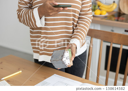 female architect or realtor holds mock up of house in her hands and photographs it for client.  138614382