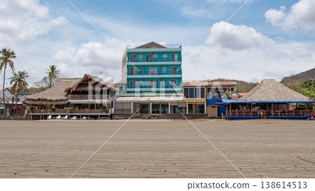 San Juan del Sur, Nicaragua - May 09, 2019: Town street with rustic house and motel. Vacation and travel. House building with straw roof. Travel destination. Street of village town. Motel buildin 138614513