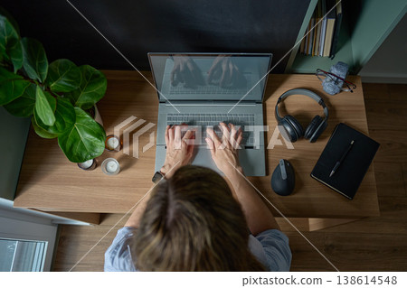Woman typing on laptop at desk in home office, viewed from above Woman typing on laptop at desk in home office, viewed from above 138614548