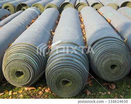 Large rolls of professional artificial turf stored outdoors for a sports field installation or renovation project 138614630