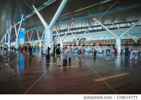The airport terminal is bustling with many travelers carrying suitcases. The airport terminal is bustling with many travelers carrying suitcases. 138614775