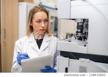 Technician examining results from advanced diagnostic analyzer HPLC during laboratory analysis. Clean and organized lab environment with various scientific instruments visible in the background. 138614893
