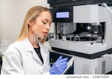 A specialist documents findings from advanced measurement instrument at biochemical analysis workstation. A specialist documents findings from advanced measurement instrument at biochemical analysis workstation. 138614897
