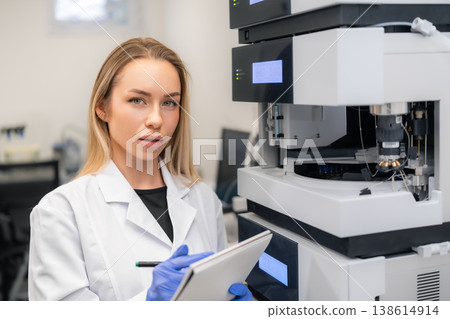 Analytical technician recording data while operating a high performance liquid chromatography system in a clinical laboratory. 138614914