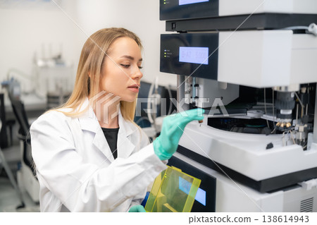 A technician calibrates an advanced HPLC chromatography system at a clinical laboratory workstation. 138614943