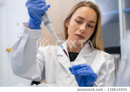 Performing precise pipetting technique to transfer red liquid samples into microcentrifuge tubes at laboratory workstation. Blood sample analysis Performing precise pipetting technique to transfer red liquid samples into microcentrifuge tubes at laboratory workstation. Blood sample analysis 138614950