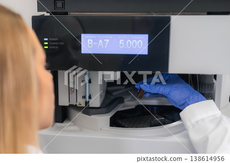 Automated liquid chromatography system performing injection of a brown sample vial at a laboratory workstation. 138614956