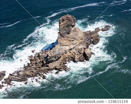 Rock formation in ocean with waves around it on sunny day Rock formation in ocean with waves around it on sunny day 138615159