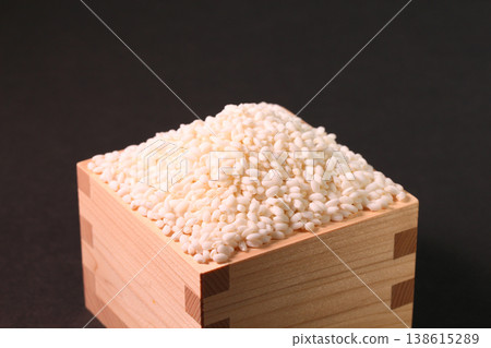 White glutinous rice piled high in a wooden box against a black background. White glutinous rice piled high in a wooden box against a black background. 138615289