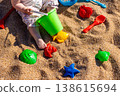 Toddler playing with plastic bucket shovel and sand molds on sandy beach. Outdoor beach photography. Childhood leisure and summer vacation concept. Design for poster, banner, postcard. Top view shot 138615694