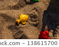 Plastic fish and ship sand molds on beach sand surface with shadow. Outdoor beach macro photography. Summer vacation and children play concept. Design for poster, banner, postcard. Macro shot 138615700