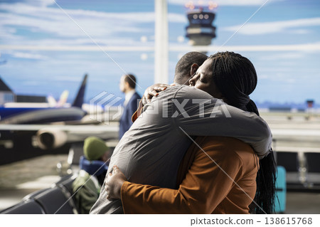 Romantic married couple hugging in busy airport waiting area, creating image of gratitude near tourists and suitcases. Quiet moment before boarding plane for long-distance flight. Romantic married couple hugging in busy airport waiting area, creating image of gratitude near tourists and suitcases. Quiet moment before boarding plane for long-distance flight. 138615768