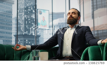 Businessman takes a break from tasks using a meditation app for stress relief. His relaxed posture shows the impact of mindfulness and self care in a high pressure corporate world. Camera B. 138615769
