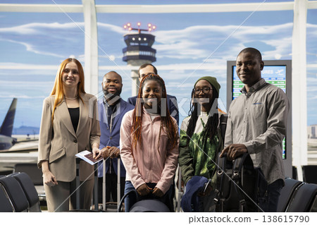 Portrait of diverse passengers in airport terminal waiting to board plane, standing in departure lounge with luggage. Travelers checking flight information on screen and their boarding pass. 138615790