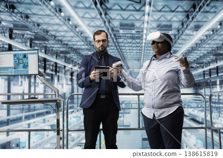 Workers using VR goggles equipment in microchip smart factory to manage resource allocation. Experts working together, using virtual reality technology to analyze CPU parts plant operations efficiency Workers using VR goggles equipment in microchip smart factory to manage resource allocation. Experts working together, using virtual reality technology to analyze CPU parts plant operations efficiency 138615819