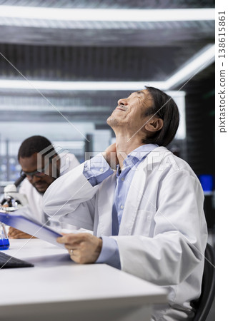 Old laboratory nanotechnology researcher feeling neck ache while using computer to process DNA patient data for clinical research. Lab expert hurt by tense muscles at PC, looking at genetic analysis 138615861