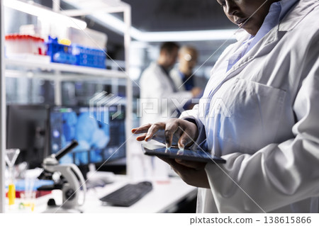 Close up of black woman performing experiments in chemistry and biology. Healthcare technology and medical research data highlight advanced research in diagnostics and scientist work. Close up of black woman performing experiments in chemistry and biology. Healthcare technology and medical research data highlight advanced research in diagnostics and scientist work. 138615866