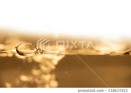 Golden liquid surface with bubble and ripples, abstract beverage background, warm light, macro waterline, luxury drink concept. Golden liquid surface with bubble and ripples, abstract beverage background, warm light, macro waterline, luxury drink concept. 138615922