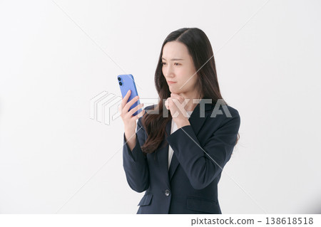 觀看智能手機的衣服的一名婦女 觀看智能手機的衣服的一名婦女 138618518