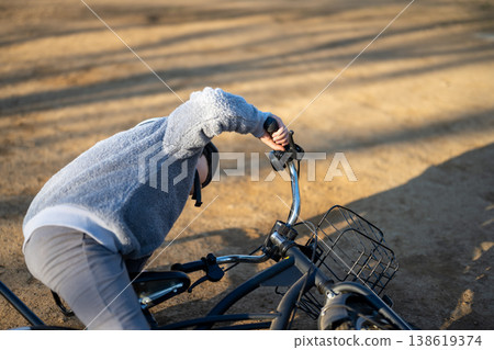 A child holding the handlebars of a bicycle. 138619374
